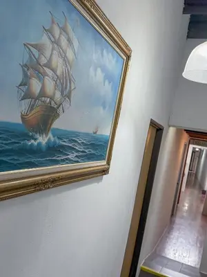 a painting of a ship in the ocean on a wall at Tonight Hotel in George Town