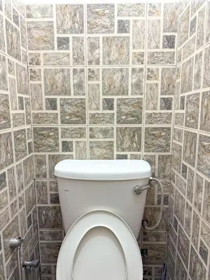 a bathroom with a toilet with a tile wall at Tonight Hotel in George Town