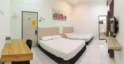 a room with two beds and a desk and a television at Raintown inn taiping in Taiping