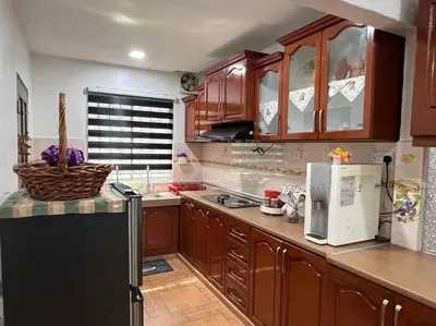 a kitchen with wooden cabinets and a black refrigerator at One's Homestay in Seri Manjung