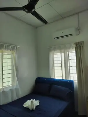 a bedroom with a blue bed with a ceiling fan at Homestay Embah Ros & Embah Lek in Hutan Melintang