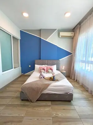 a bedroom with a large bed with a blue wall at PoP Kitty Octagon Premium Ipoh Town Center 2BR by Grab A Stay in Ipoh