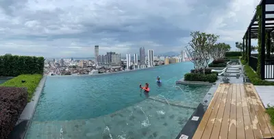 a person in a swimming pool with a city in the background at Beacon Executive Suites #CozyFamilyStay #RoofTopPool #13 in George Town
