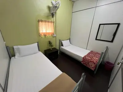 a small room with two beds and a fan at De Cameron Guest House in Tanah Rata