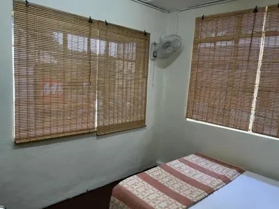 a bedroom with two windows and a bed in it at De Cameron Guest House in Tanah Rata