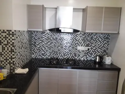 a kitchen with white cabinets and black and white tiles at Lovers Island homestay in Batu Ferringhi
