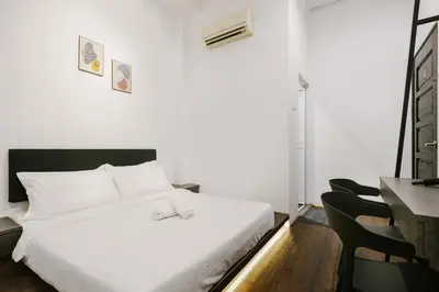 a white bed in a room with a table and chairs at Kangsar Inn 73 in George Town