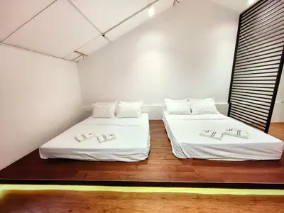 two beds in a room with white walls and wood floors at Kangsar Inn 73 in George Town