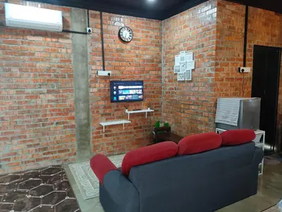 a living room with a couch and a clock on a brick wall at Studio Amani 1 Permatang Pauh in Permatang Pauh