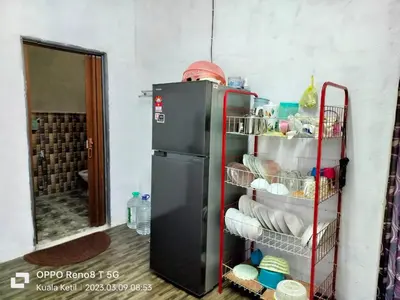 a small refrigerator in a room with a shelf at Myrol Homestay Kuala Ketil in Kuala Ketil