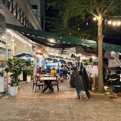 a patio with people sitting at tables under a tent at 6PAX ONE BEDROOM SOHO near USM SPICE ARENA PANTAI SPECIALIST AIRPORT in Bayan Lepas