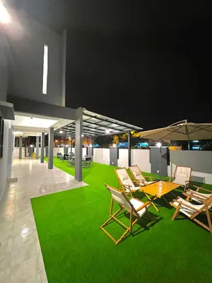 a patio with chairs and a table and green grass at Entire Vacation Home with landscape garden in Sitiawan