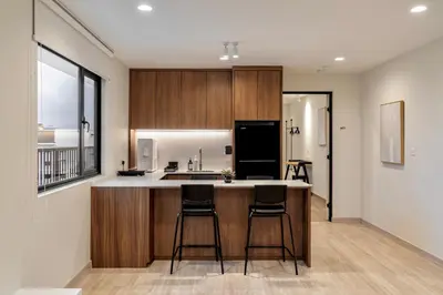 a kitchen with wooden cabinets and a kitchen island with bar stools at Codrington House - Boutique Apartments in George Town