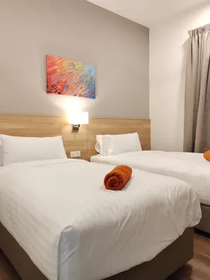 two beds in a hotel room with a towel on them at Ipoh Sunway Onsen Suites and Tambun Guesthouse , 3-14pax 2parking by IWH in Ipoh