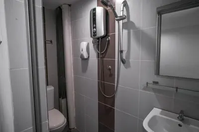 a bathroom with a shower with a phone on the wall at Heritage Inn in George Town