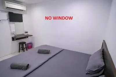 a room with a bed with a no window sign on the wall at Heritage Inn in George Town