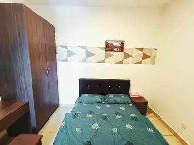a bed with a green comforter in a bedroom at Freezing Point Homestay @ Palas Horizon Residence in Cameron Highlands