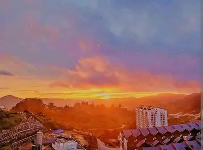 a sunset with a rainbow in the sky over a city at Freezing Point Homestay @ Palas Horizon Residence in Cameron Highlands