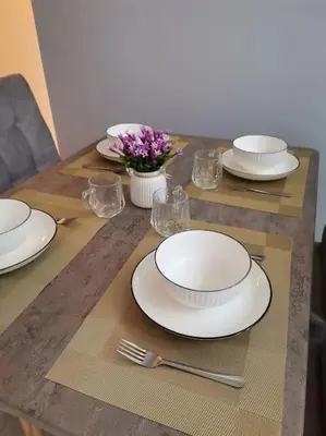 a table with white plates and flowers on it at Casa Apartment @ Ipoh \u3010\u6021\u4fdd\u6c11\u5bbf\u3011 in Ipoh