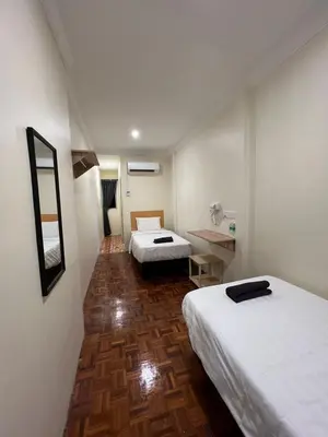 a hotel room with two beds and a desk at Homestay Suria in Kuala Kangsar