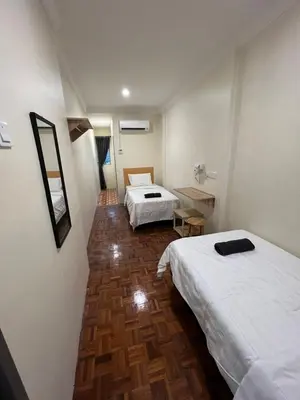 a room with two beds and a wooden floor at Homestay Suria in Kuala Kangsar
