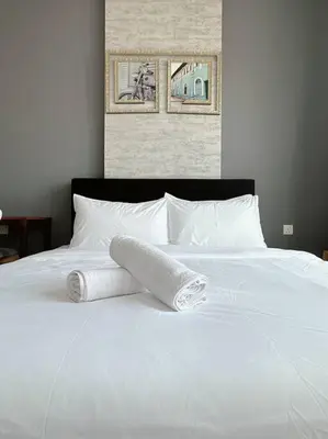 a white bed with two rolled towels on it at Ipoh Town - Octagon Cozy Deluxe Homestay in Ipoh