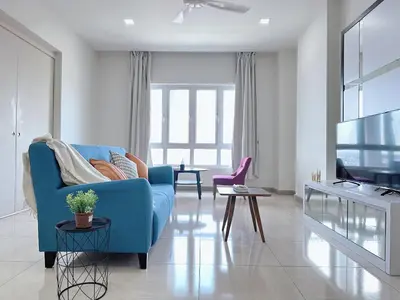 a living room with a blue couch and a tv at Ipoh Town - Octagon Cozy Deluxe Homestay in Ipoh