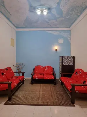 a room with two red chairs and a ceiling at HELLO HOMESTAY in Nibung Tebal