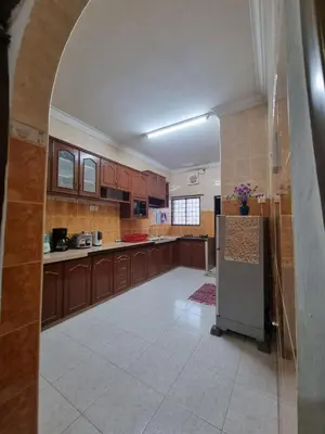 a large kitchen with wooden cabinets and a refrigerator at HELLO HOMESTAY in Nibung Tebal