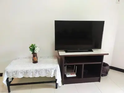 a tv sitting on a stand with a table with a small table sidx at Have a pleasant stay with Bayu Emas Homestay in Batu Ferringhi