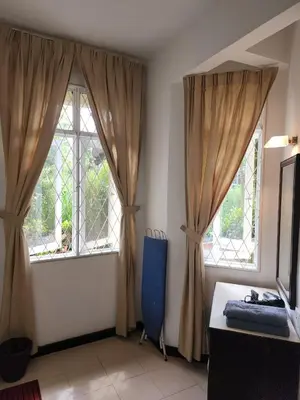 a room with two windows and a blue chair at Have a pleasant stay with Bayu Emas Homestay in Batu Ferringhi