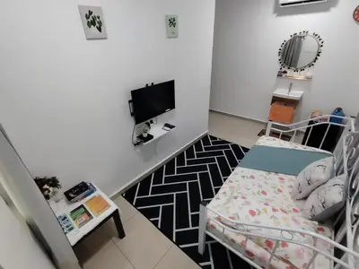 a small room with a bed and a tv at Sri MaLati Homestay and Event Space in Balik Pulau