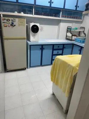a kitchen with a refrigerator and a table with a yellow towel at Family House in Jelutong
