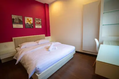 a bedroom with a white bed with a red wall at Cozy Gurney Georgetown Private Apartment Penang in George Town
