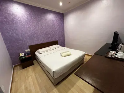 a bedroom with a bed and a purple wall at GOA INN HOTEL SDN BHD in Gua Musang