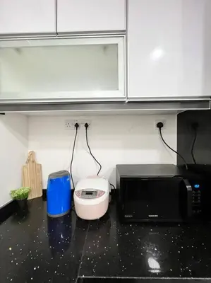 a kitchen with a black counter top with a microwave at Lily King (modern and comfy) in Tanah Rata
