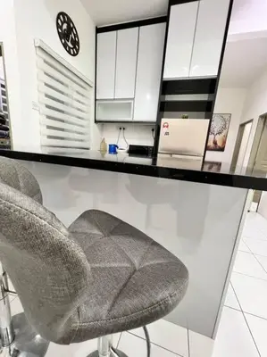 a kitchen with two chairs and a counter with white cabinets at Lily King (modern and comfy) in Tanah Rata