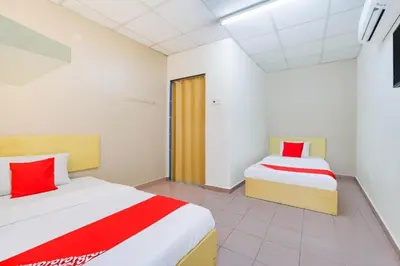 two beds in a room with red and white sheets at CP Hotel in Butterworth