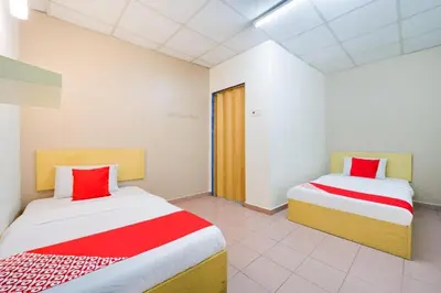 a bedroom with two beds with red and white sheets at CP Hotel in Butterworth
