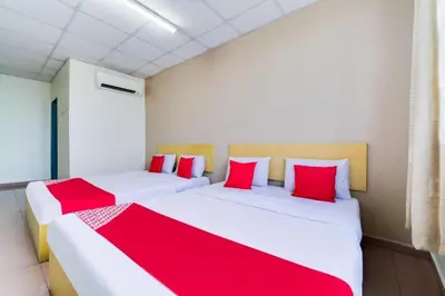 two beds in a room with red and white pillows at CP Hotel in Butterworth