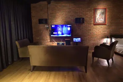 a living room with a tv and a brick wall at The Label Suites Ipoh in Ipoh
