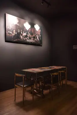 a dining room table with chairs and a painting on the wall at The Label Suites Ipoh in Ipoh