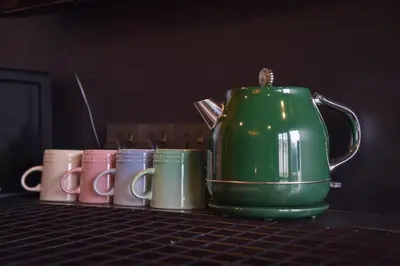 a green tea pot and several different colored mugs at The Label Suites Ipoh in Ipoh