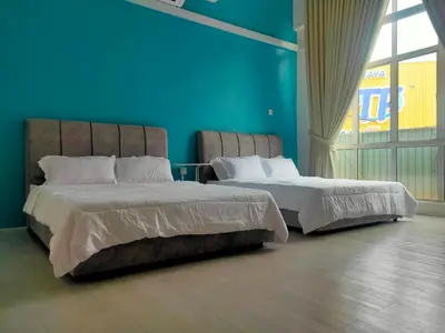 two beds in a room with a blue wall at SALAM Homestay D'Gerik in Gerik