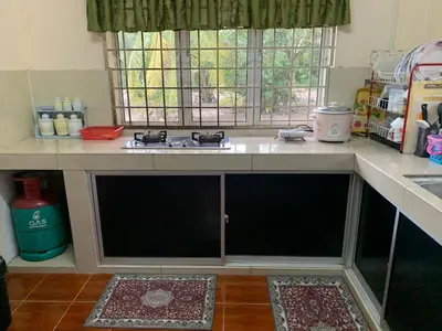 a kitchen with a counter with a stove and a window at D’baroh Homestay in Kampong Tanjong Karang