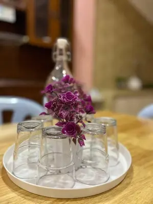 a plate with three glasses and a vase with purple flowers at Casa Indera in Kampung Bota Kiri