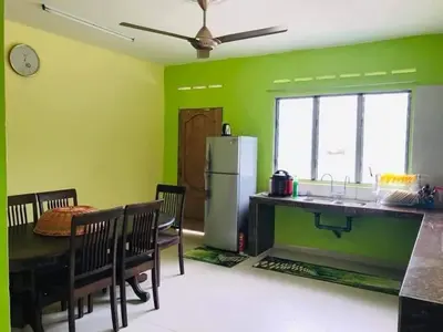 a kitchen and dining room with green walls at Hijau Homestay in Sungai Besar