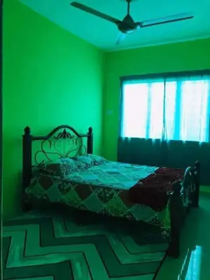 a green bedroom with a bed and a window at Hijau Homestay in Sungai Besar
